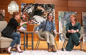 Three people sitting on a stage engaged in active conversation.