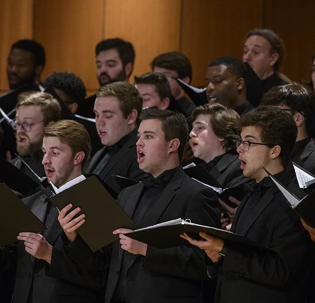 Members of the men's glee sing together during a concert