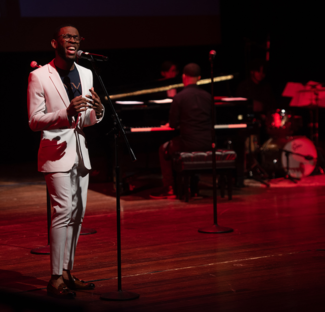 man sings in front of a microphone on stage