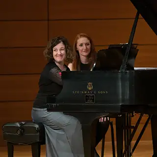 A music professor laughs with a student during class