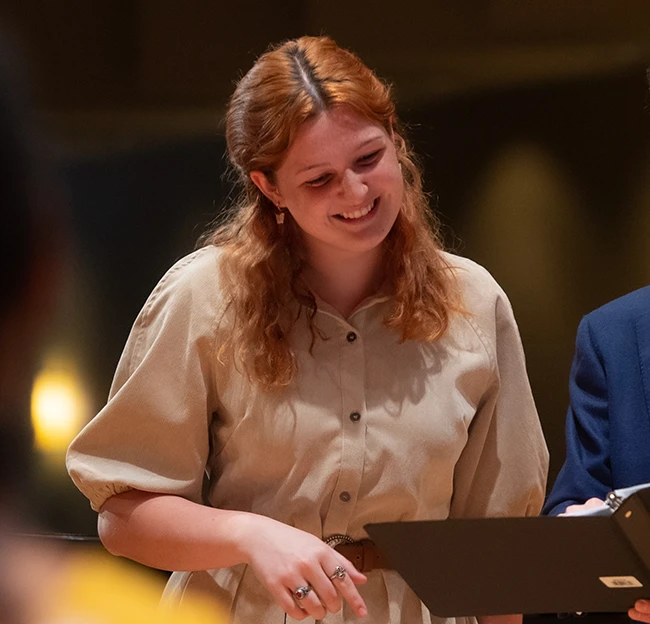 A student smiles as she looks at her professor's book