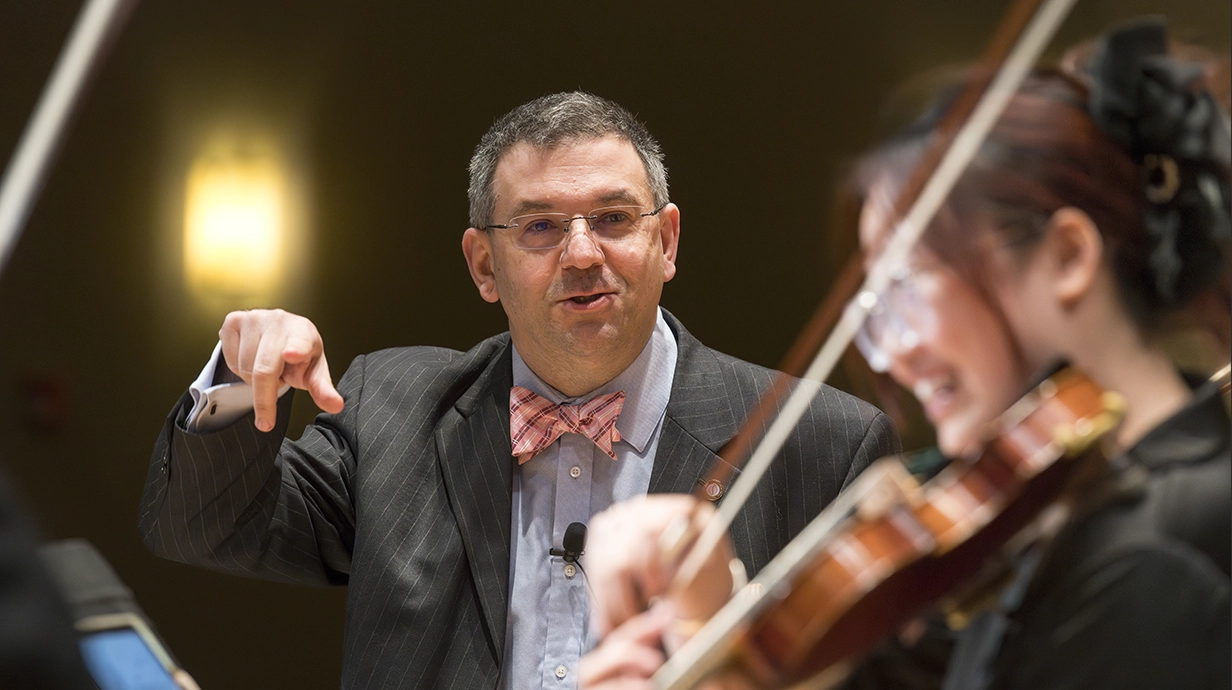 orchestra director instructs violin student