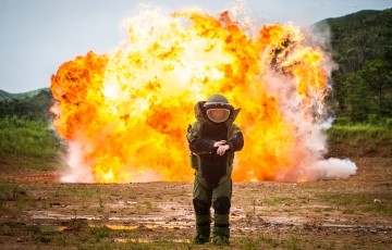 explosion in a field behind an explosives expert