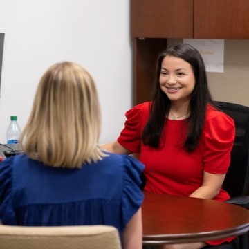 image of an academic advisor sitting in an office smiling at a student