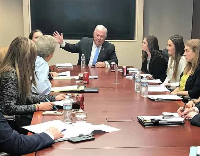 Haley Barbour gesturing and talking while seats around a table with students