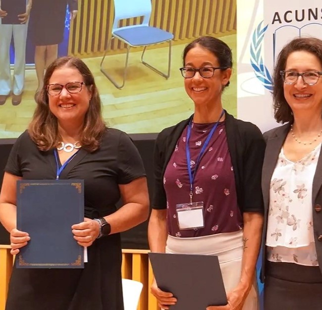 image Susan Allen standing with two other people and holding an award and smiling at the camera