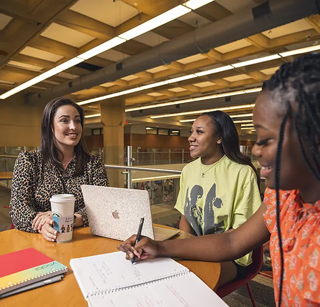 Professor and two students sitting at a table talking