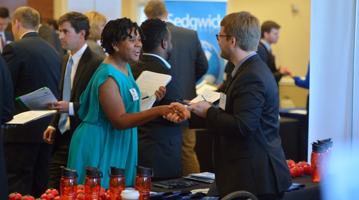 student shaking the hand of a company rep at a career fair