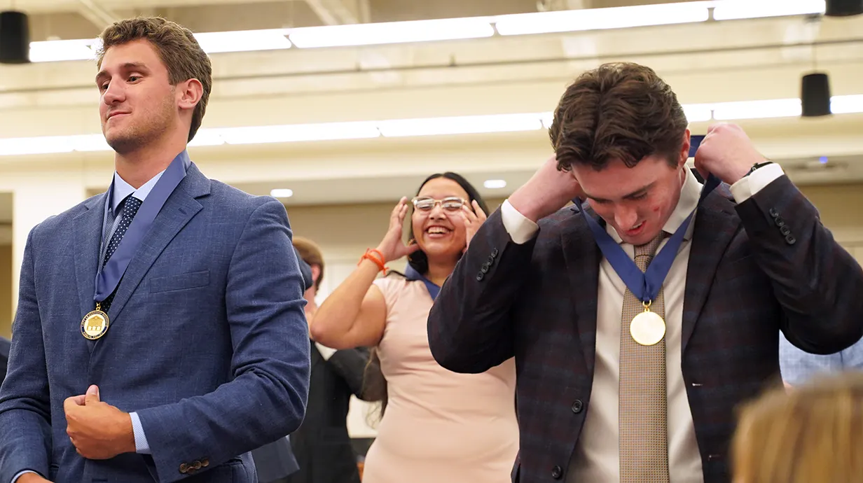 Three students standing, receiving medals