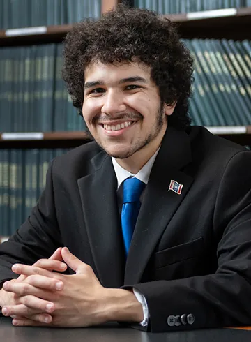 Portrait of Andy Flores seated in front of book shelves