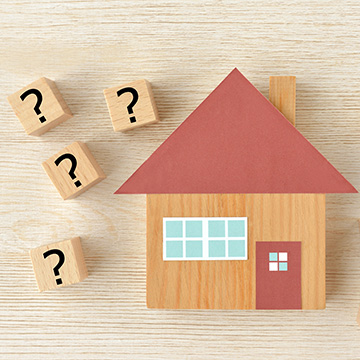 toy wood house with question marks around it