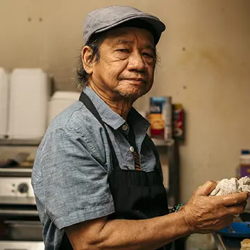 Portrait of man in apron holding a dish rag
