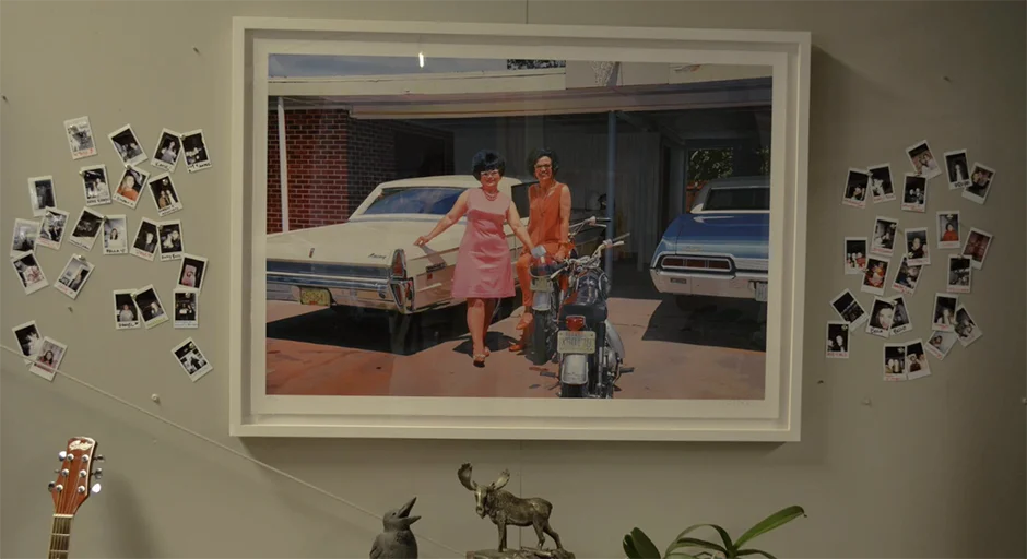 Framed photo on a wall with polaroid photos tacked to wall