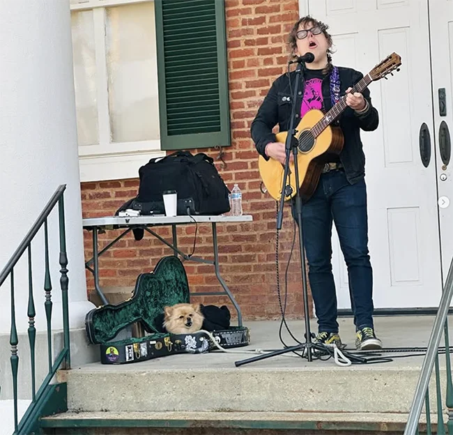person holding a guitar and singing on outdoor steps