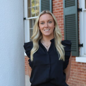 Liza-Handly Hughes in front of white column and brick wall