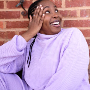 portrait of person turned to side with hand on face. Background is red brick