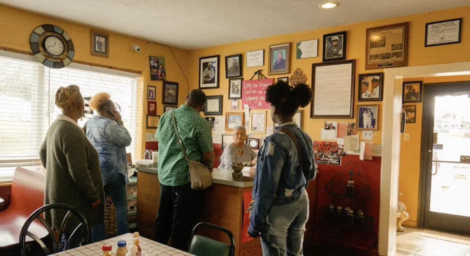 Group of four people facing a woman sitting at a cashier desk
