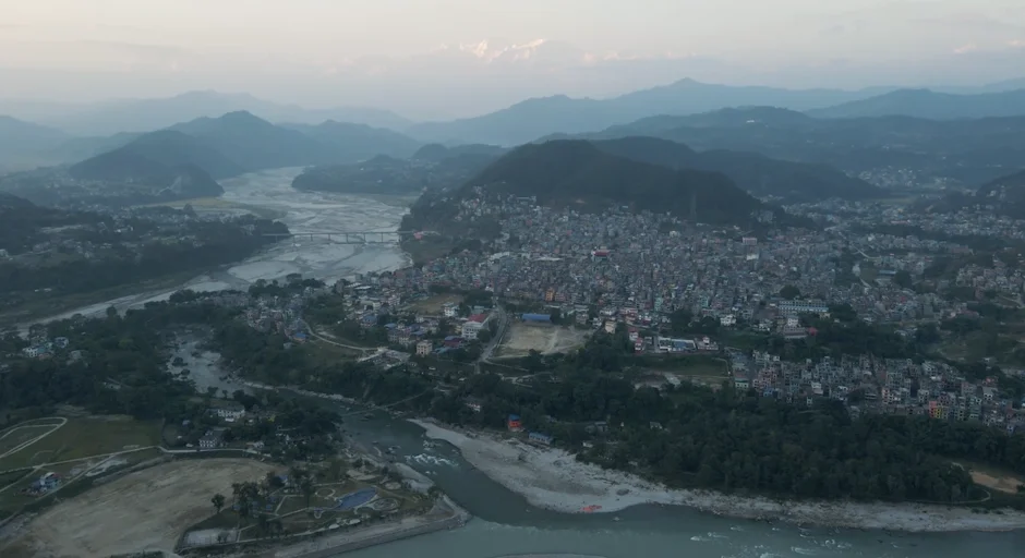 Aerial view of city surrounded by water on one side and mountains on the other