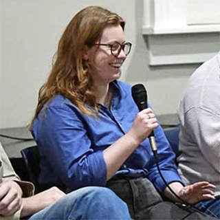 person sitting on stage holding a microphone