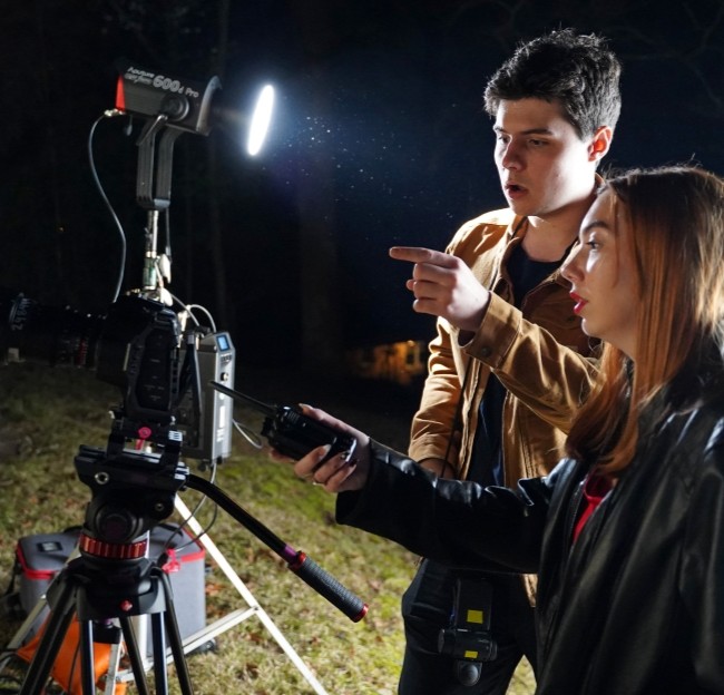 students working together on the camera lighting equipment at an evening film shoot