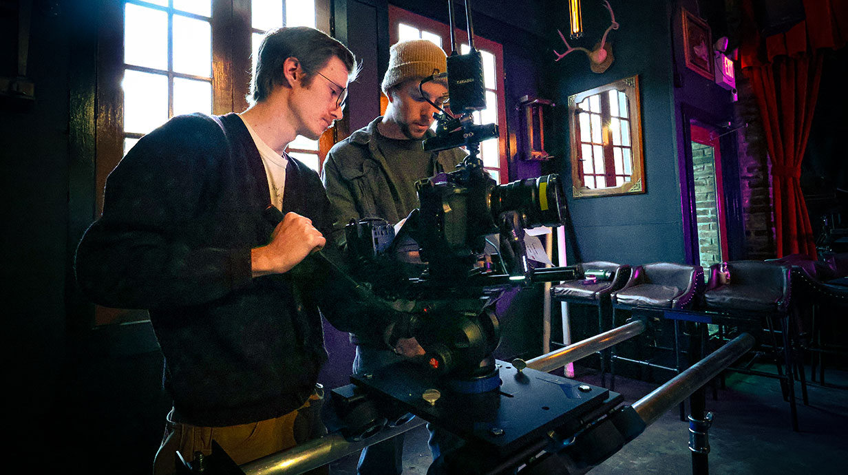 two men holding camera equipment inside a bar