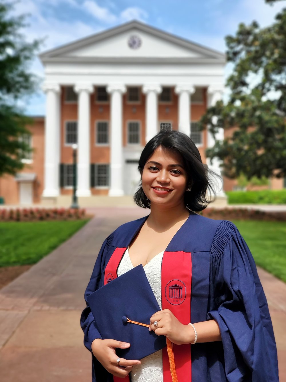 international student standing in cap and gown in front of the Lyceum building