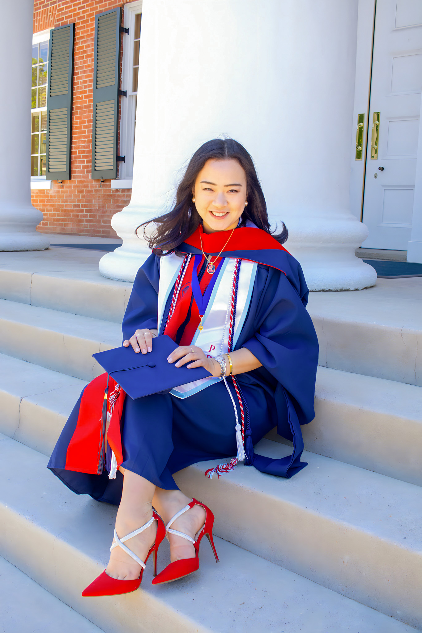 Student Jiwon Lee poses in front of the Lyceum building wearing here masters graduation attire.