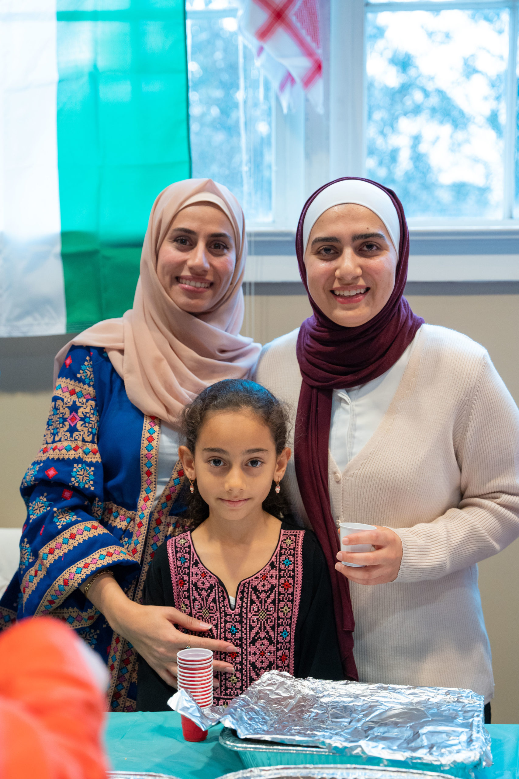 Two women and a young girl smile during international food event