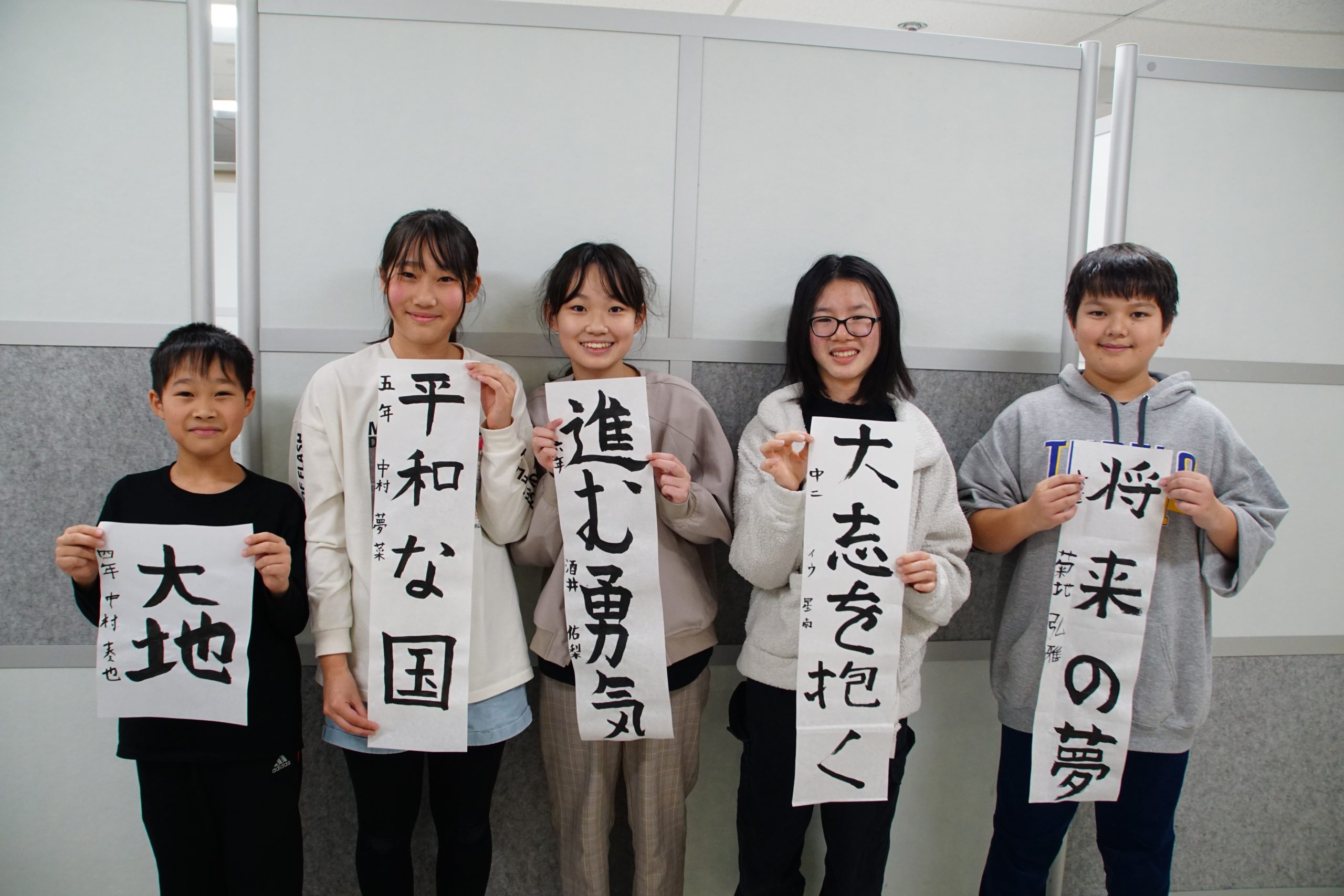 Japanese students hold up traditional Japanese calligraphy