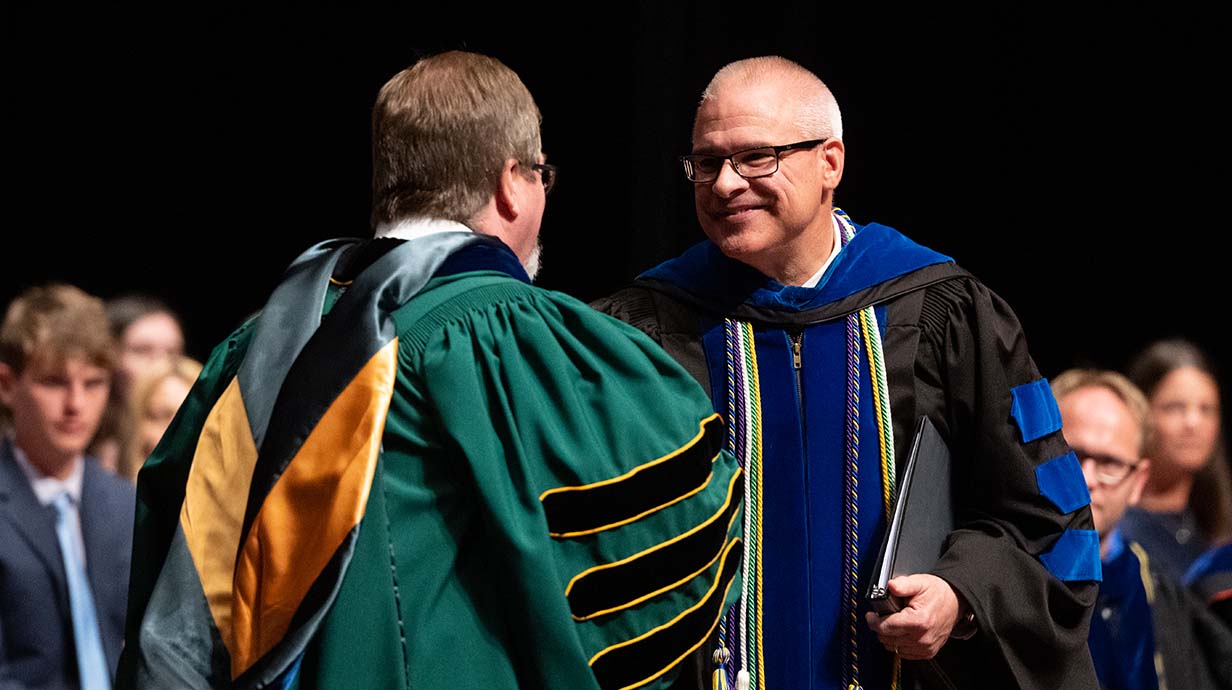 Noel Wilkin shaking the hand of Pharmacy Administration professor John Bentley during an awards ceremony