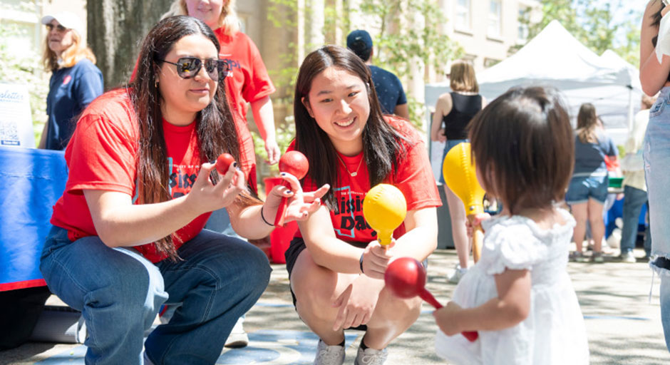 Two volunteers give materials to a young attendees at Mississippi Day