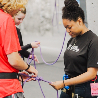 Outdoors employee assisting climbers.