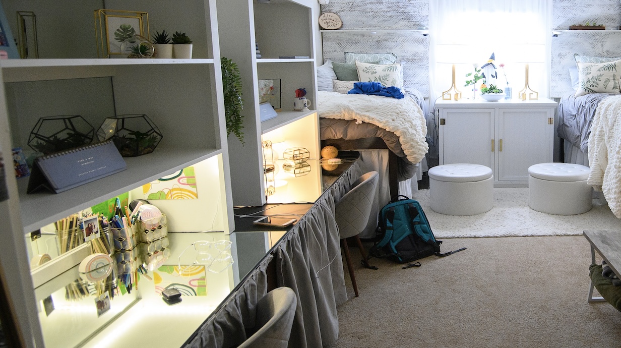 Two desks with hutches in front of two beds and a window