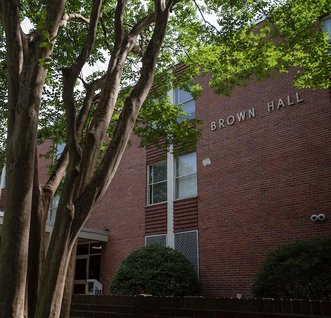 Photo of the outside of Brown Hall with a tree in the front. 