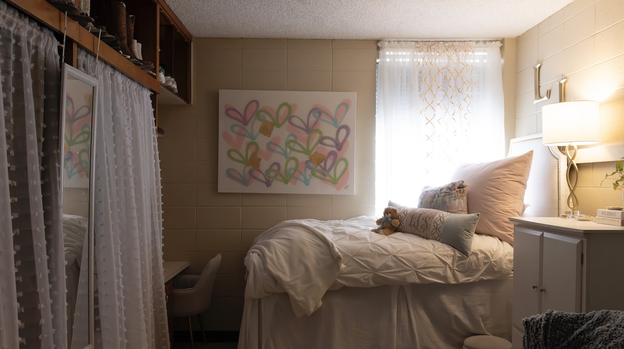 Photo of bed and window next to a desk and closet. 