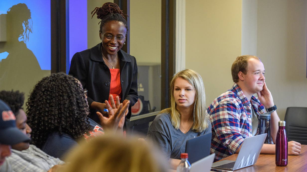 An instructor works with students in a seminar-style classroom