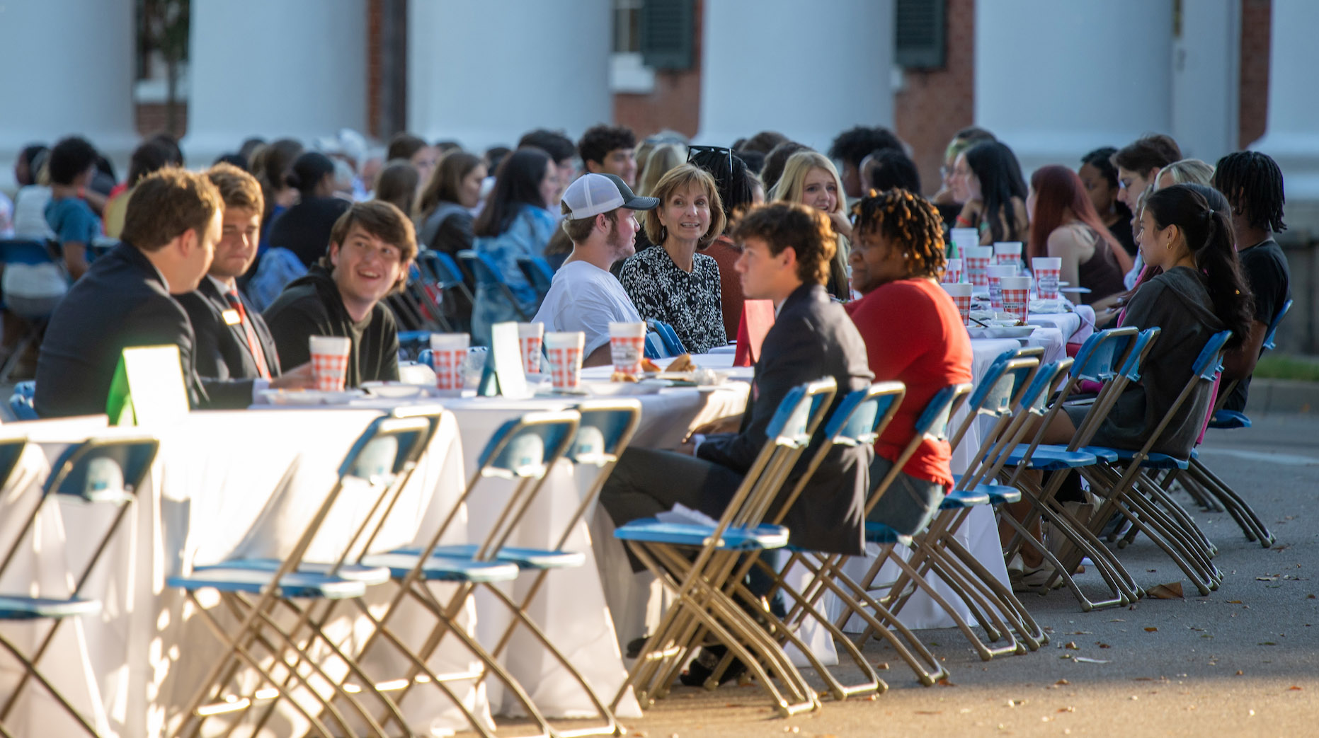 students and faculty sit at a long table outside