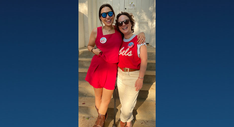 Two women stand on the concrete steps of a building entrance.