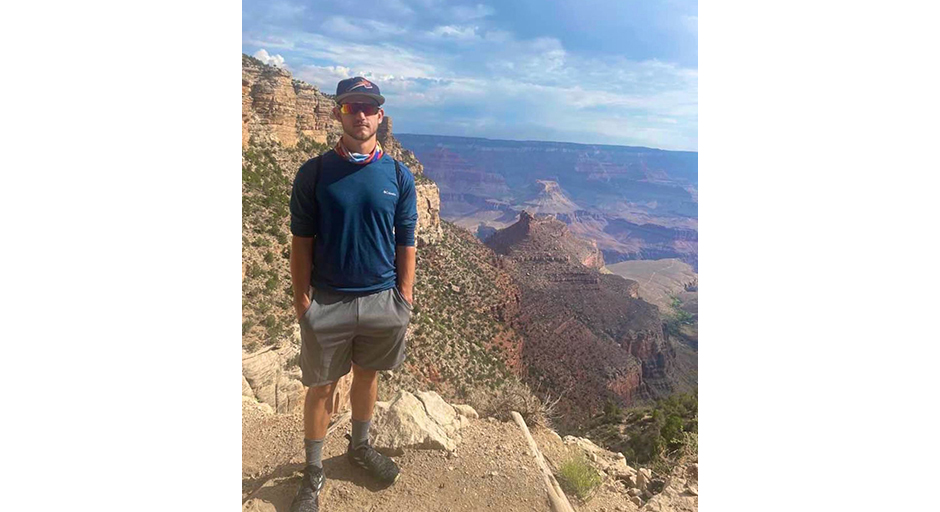 A young man stands on a trail in the Grand Canyon.