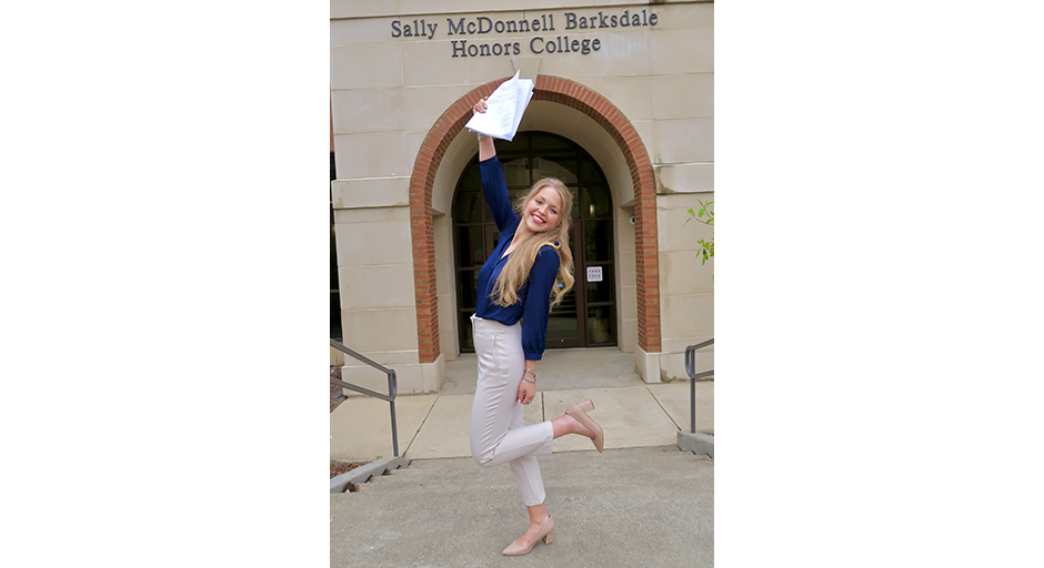 A young woman dances and waves a sheaf of papers in the air.