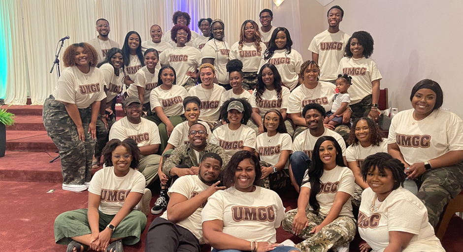 A group of young people all wearing shirts that read 'UMGC' pose for a photo.