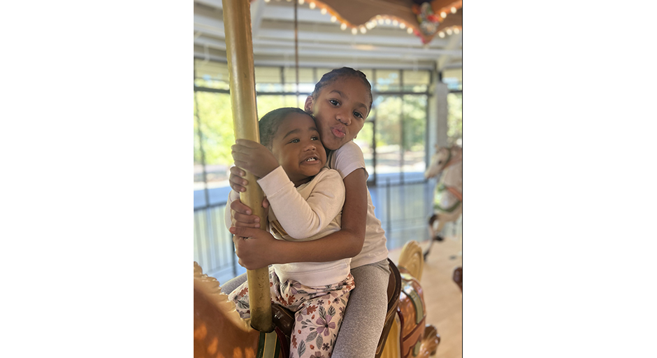 Two children ride a carousel horse.