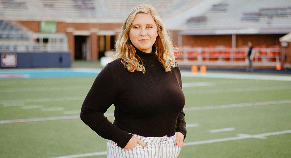 A young woman stands inside a stadium.