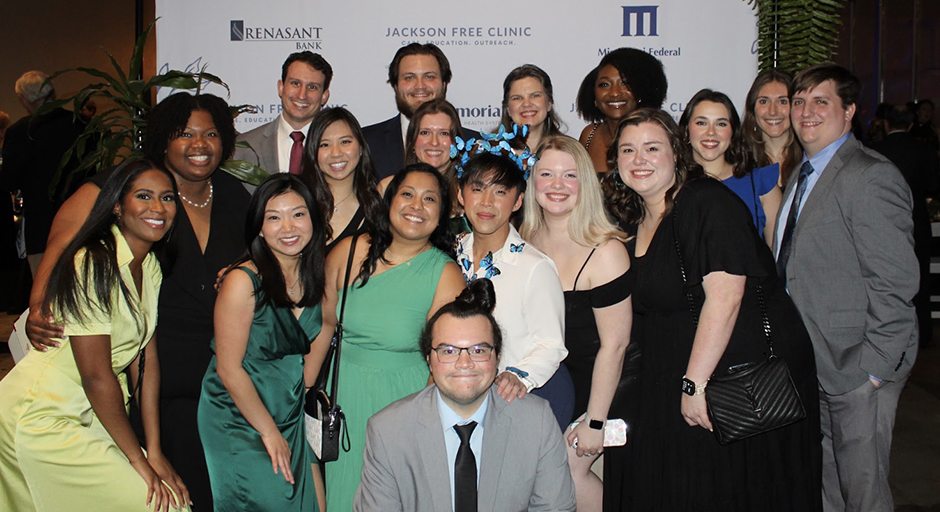 A large group of people pose fopr aphoto at a formal gala.