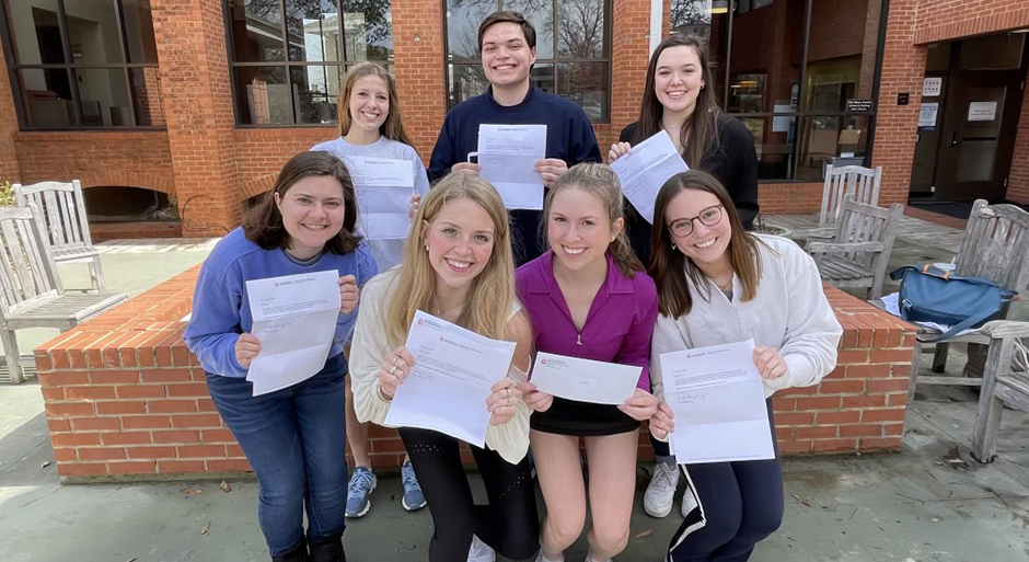 A group of young people celebrate while holding up letters.