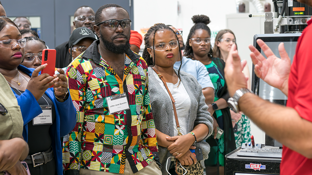 Four fellows listen to a speaker talk during the Mandela fellows visit tot he Center for Manufacturing Excellence. 