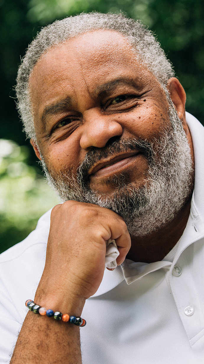 A man wearing a white shirt rests his chin on his fist.