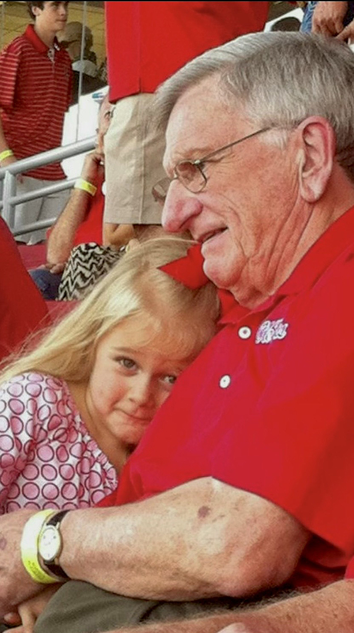 A man and a young girl sit together in a football stadium.