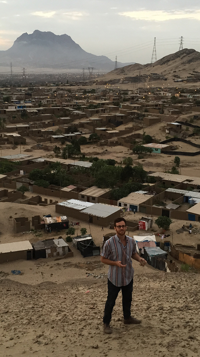 A man stands on a hillside overlooking a village.