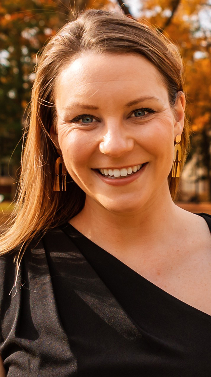Headshot of a woman wearing a black top standing outdoors.